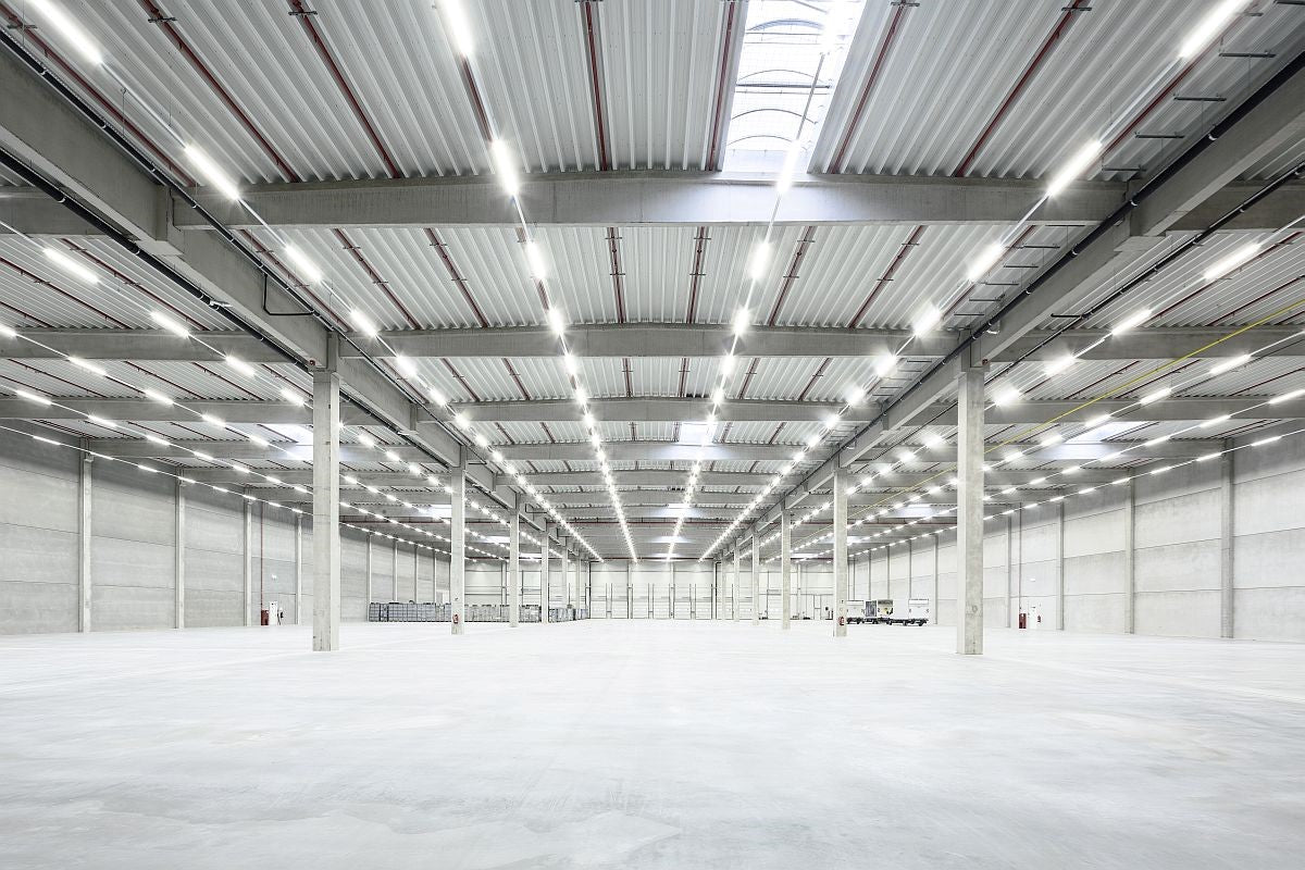 Sistema de alumbrado LED industrial instalado en almacén amplio, ejemplo de diseño a medida con tecnología de alta eficiencia energética.